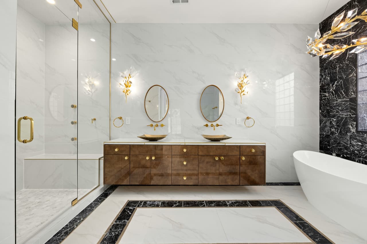 Green vanity, brass hardware, and marble shower detail in a luxury bathroom remodel.
