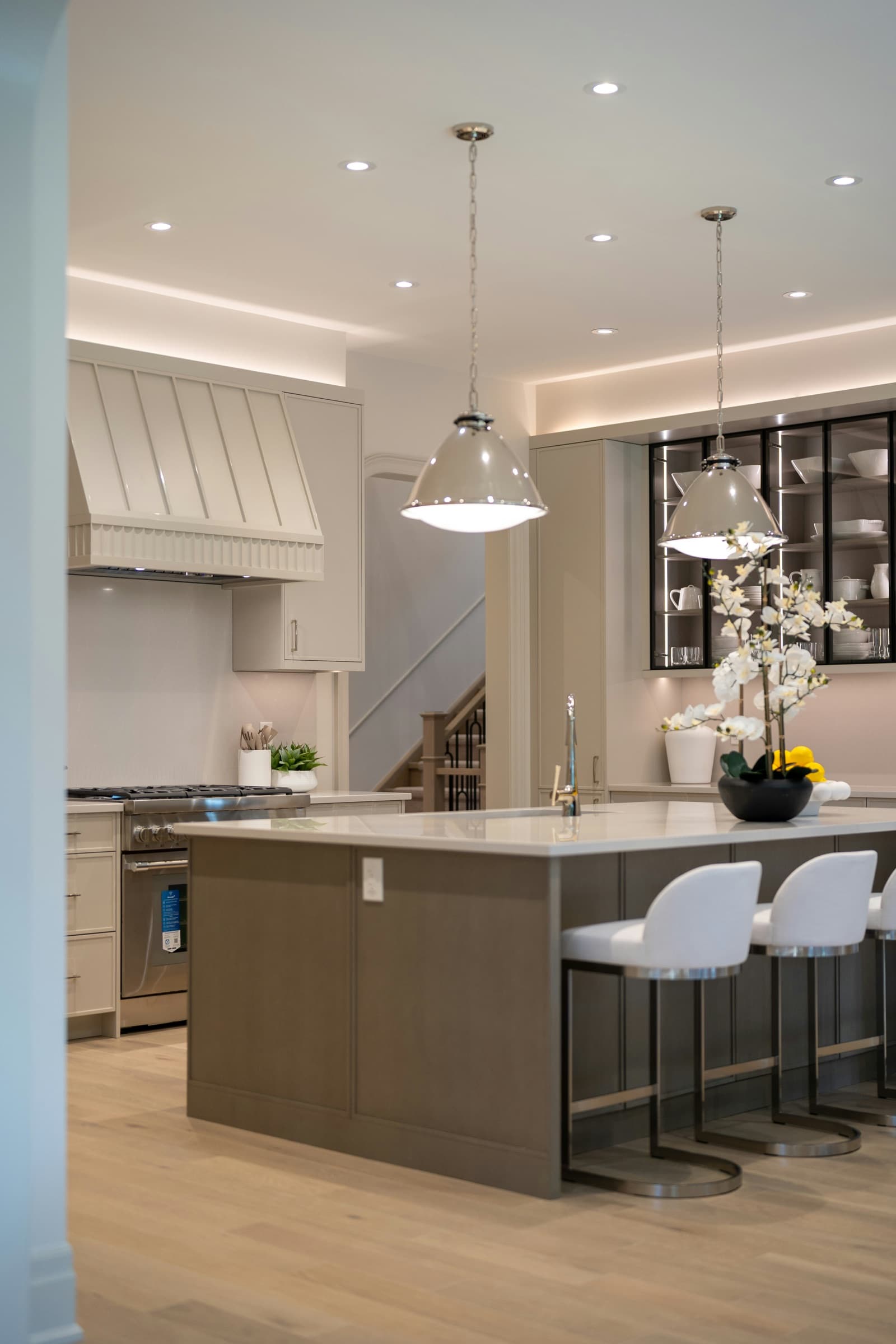 Warm wood kitchen cabinetry, marble counters, professional range, and stone tile floor.