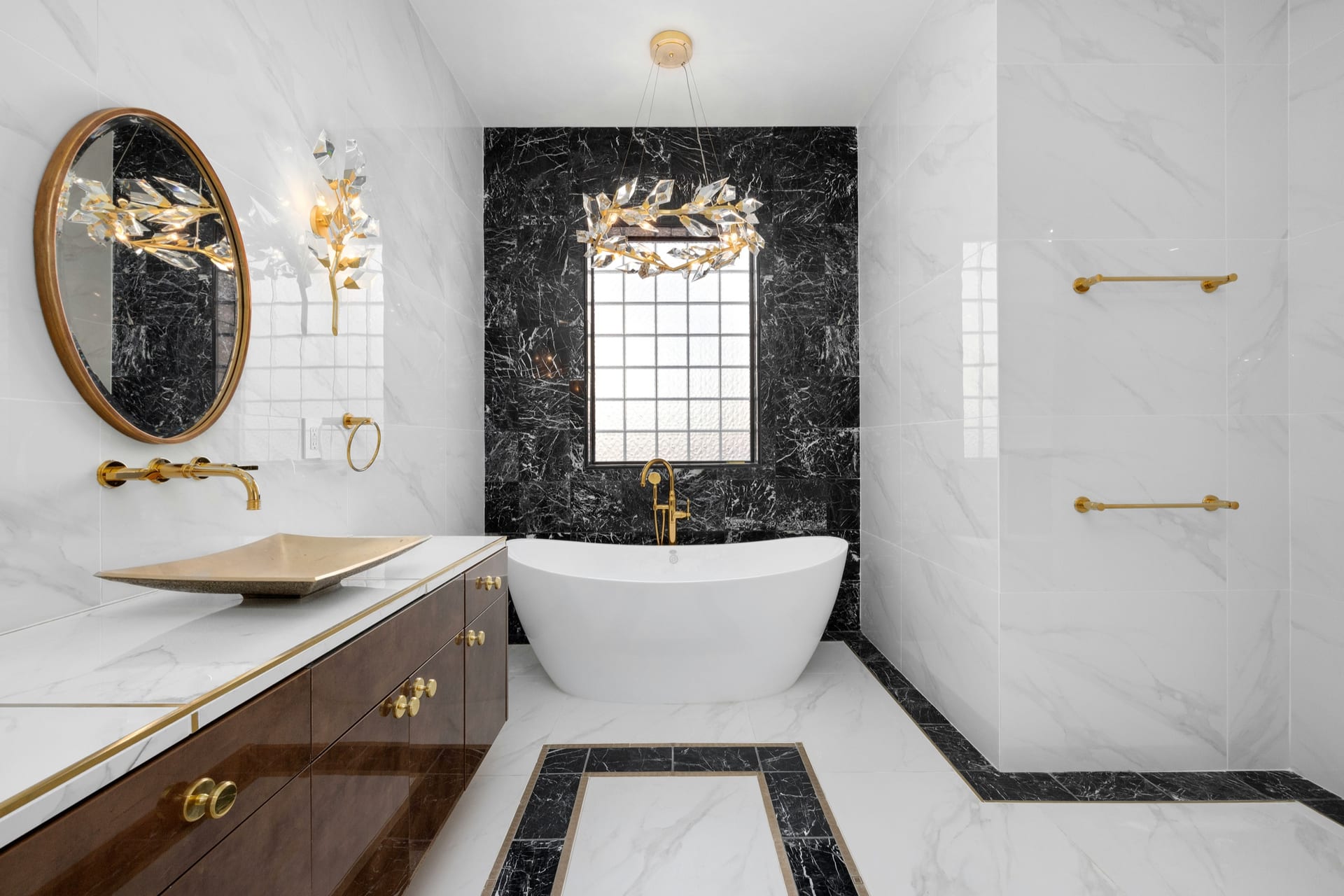 Primary bathroom remodel with freestanding tub, black marble accent wall, and brass fixtures.