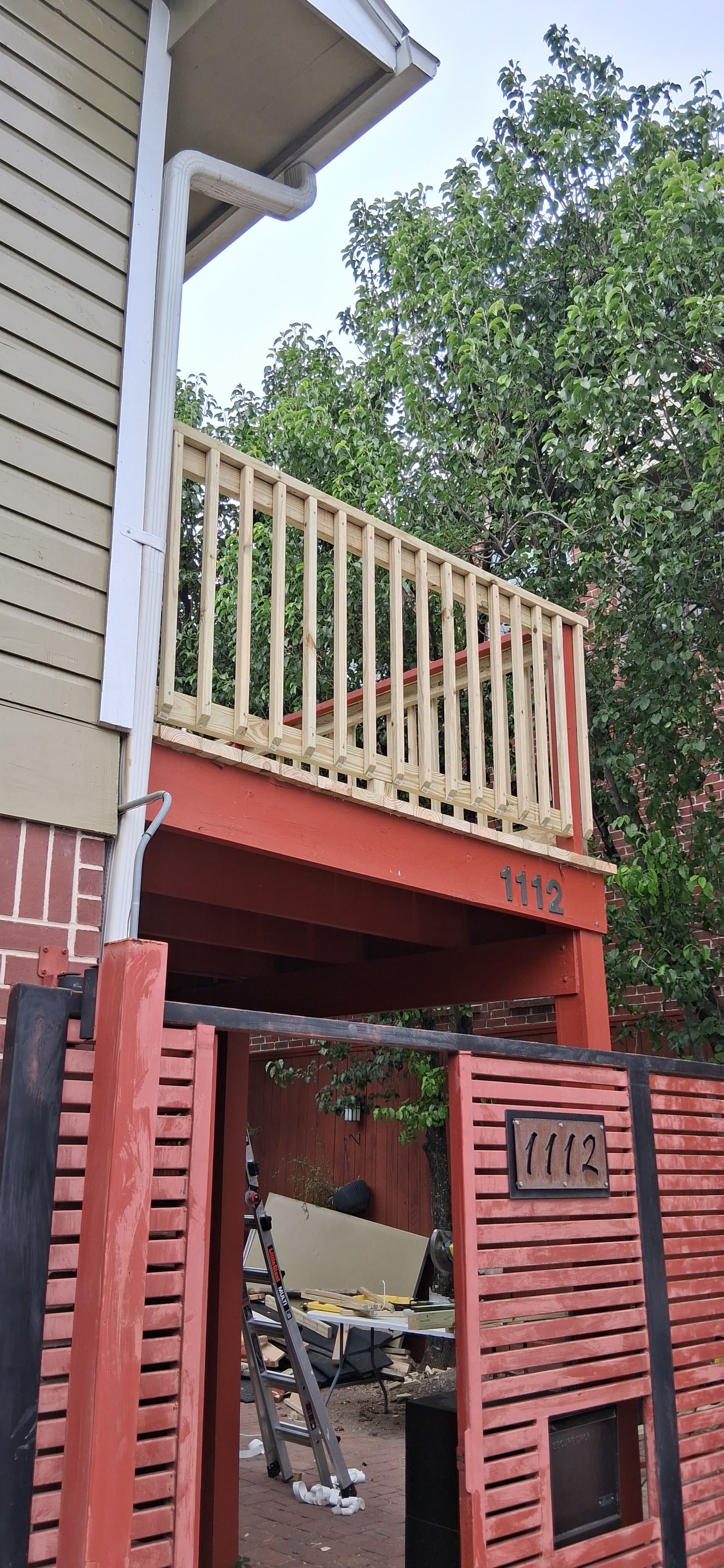 Newly installed wood railing on an elevated deck beside an exterior stair opening.