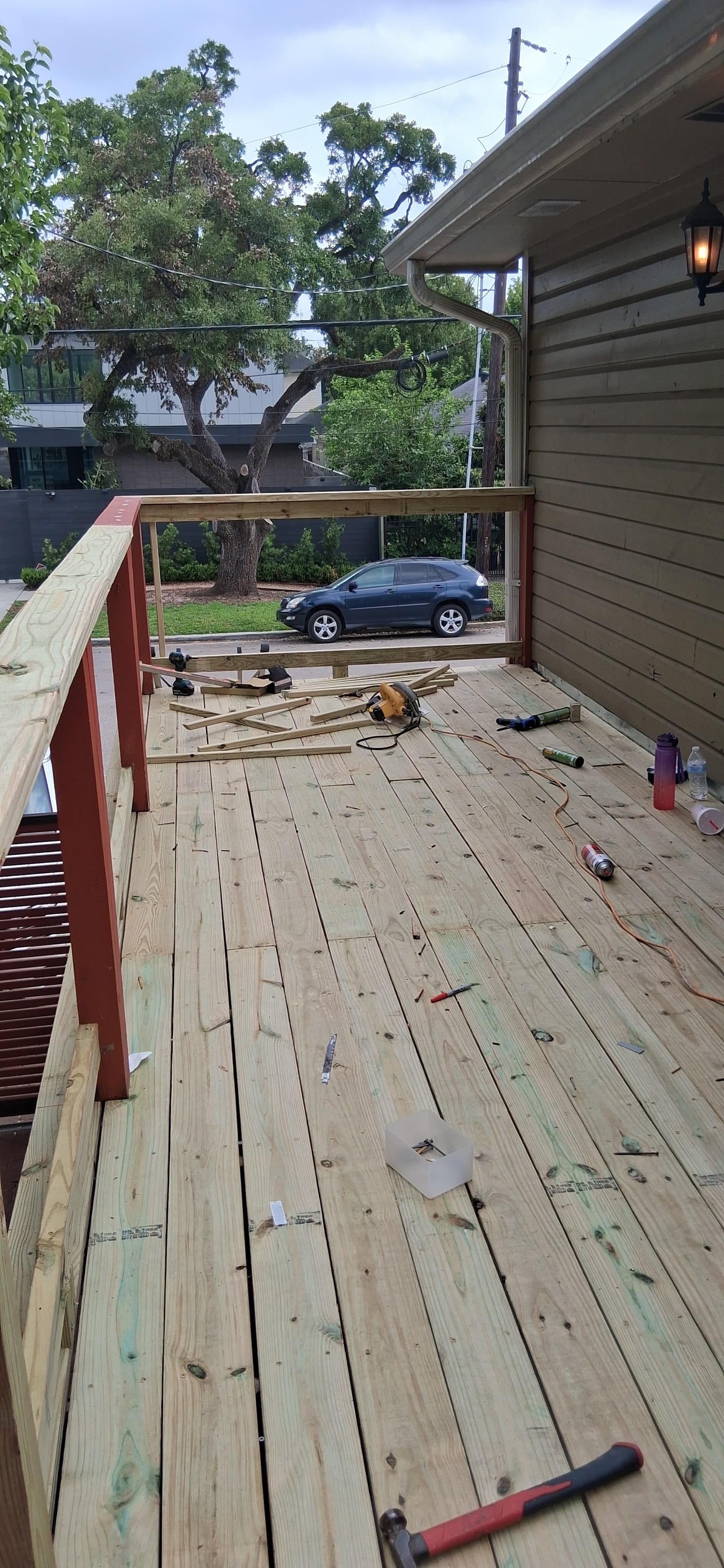 Wood deck surface with railing framing underway and tools on the boards.