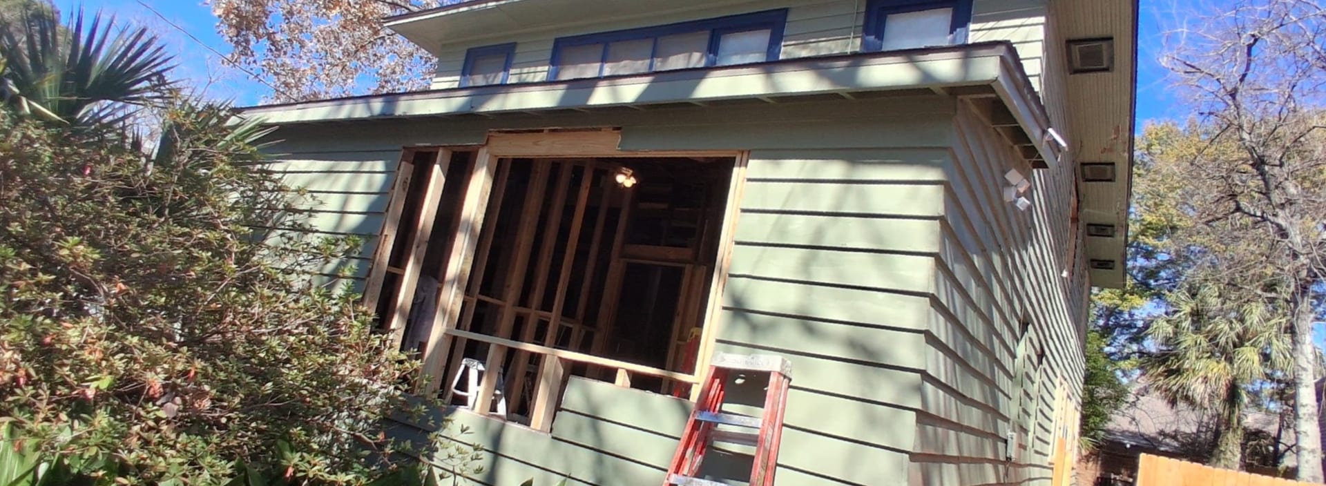 Front exterior of a house with multiple upper window openings during installation work.