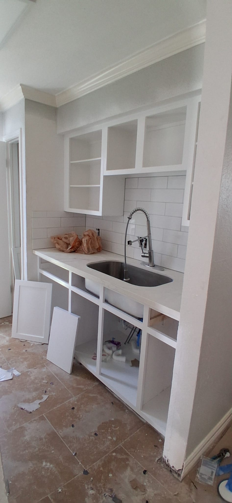 Kitchen sink and cabinet installation in progress before cabinet doors and finish cleanup.