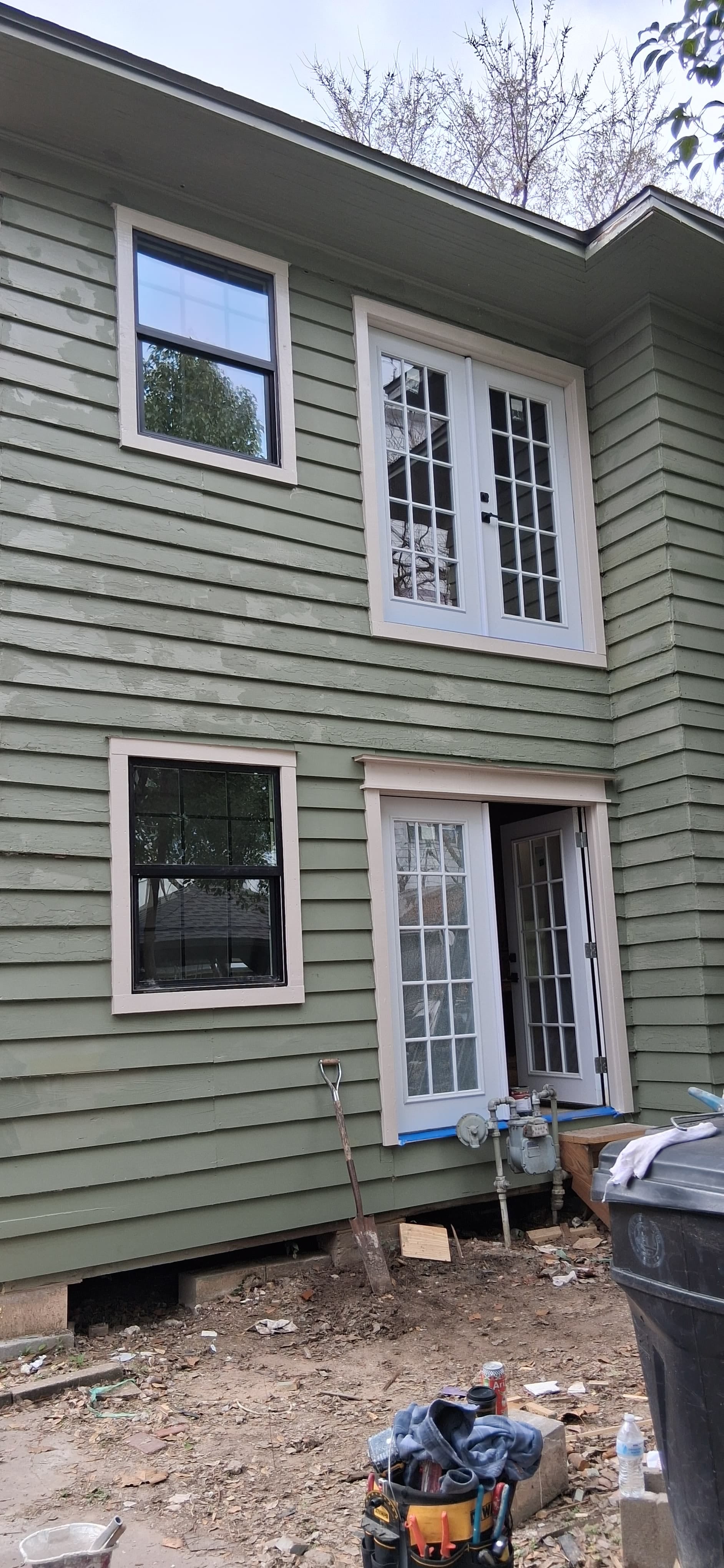 Rear exterior of a house after window and door installation with siding repair around the openings.