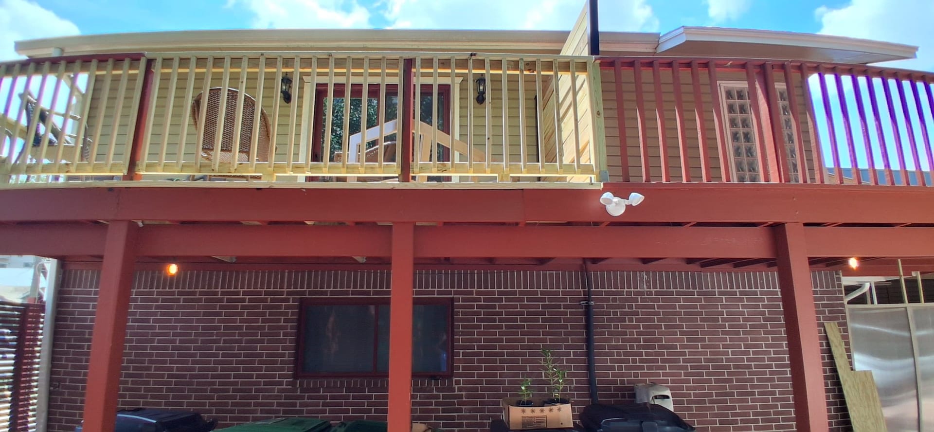 Second-story deck railing framing in progress above a covered outdoor area.