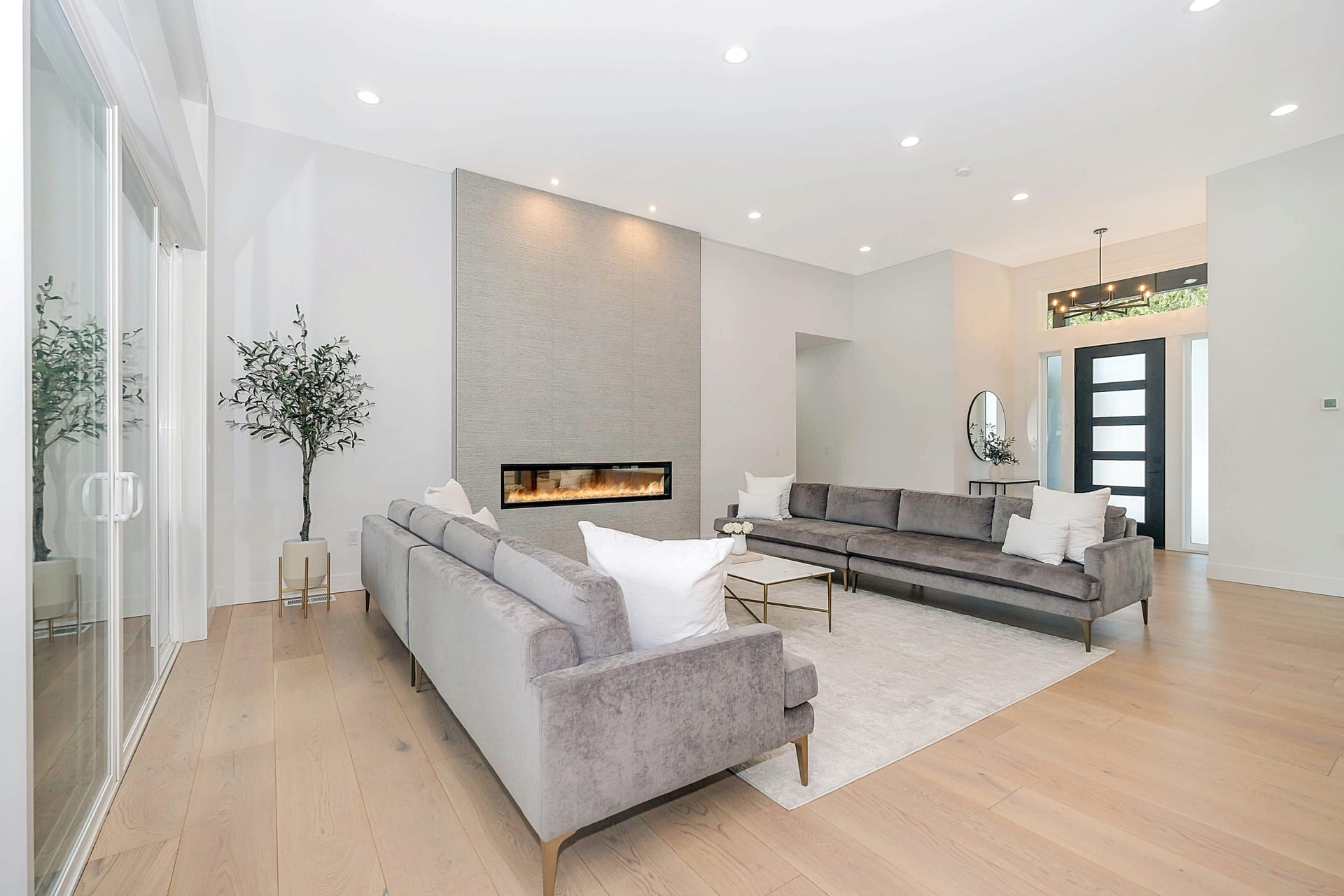 Bright living room remodel with pale wood flooring, fireplace wall, and refined neutral finishes.