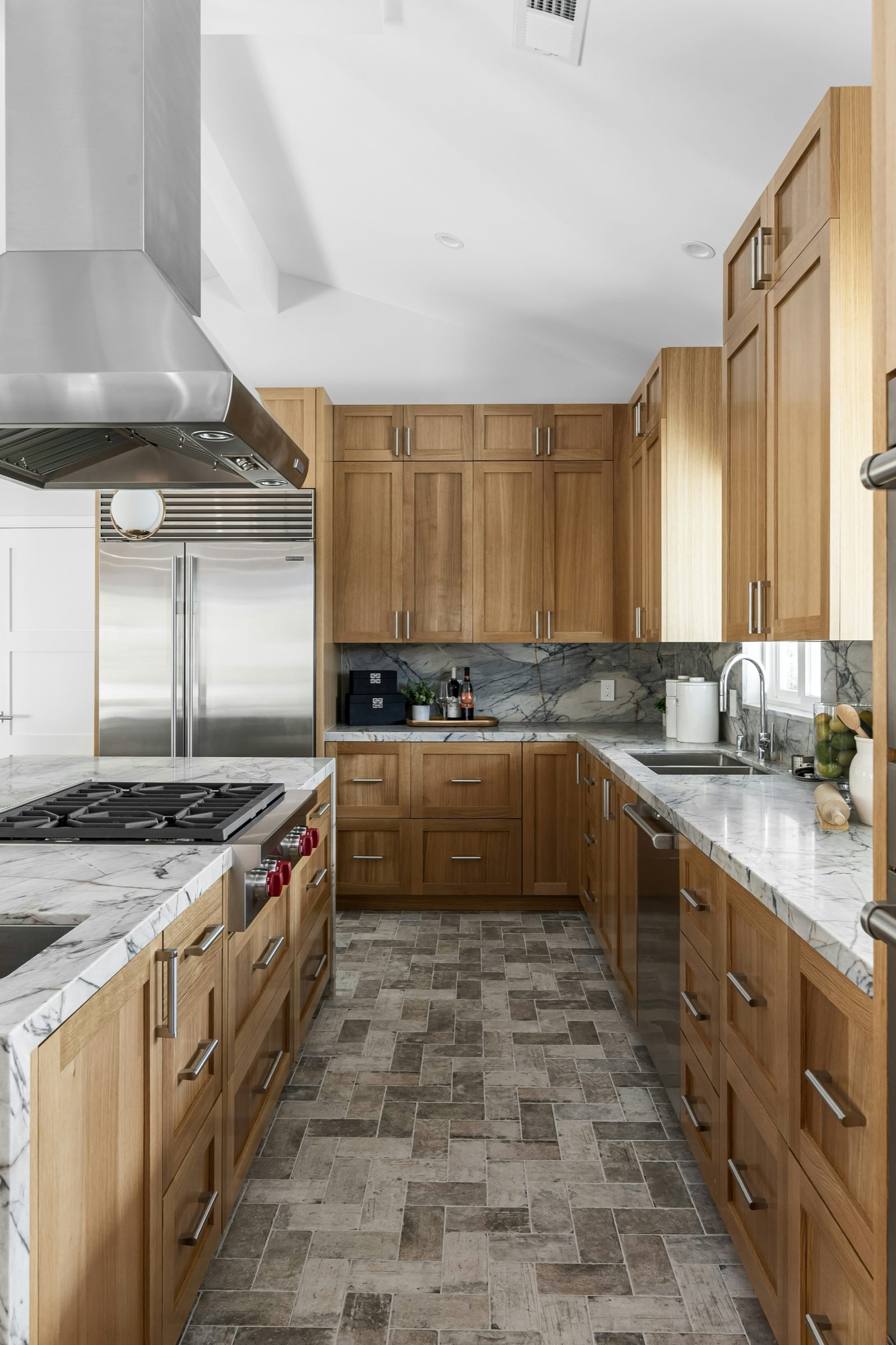 White kitchen cabinetry with brass pulls, white tile backsplash, and styled countertop detail.