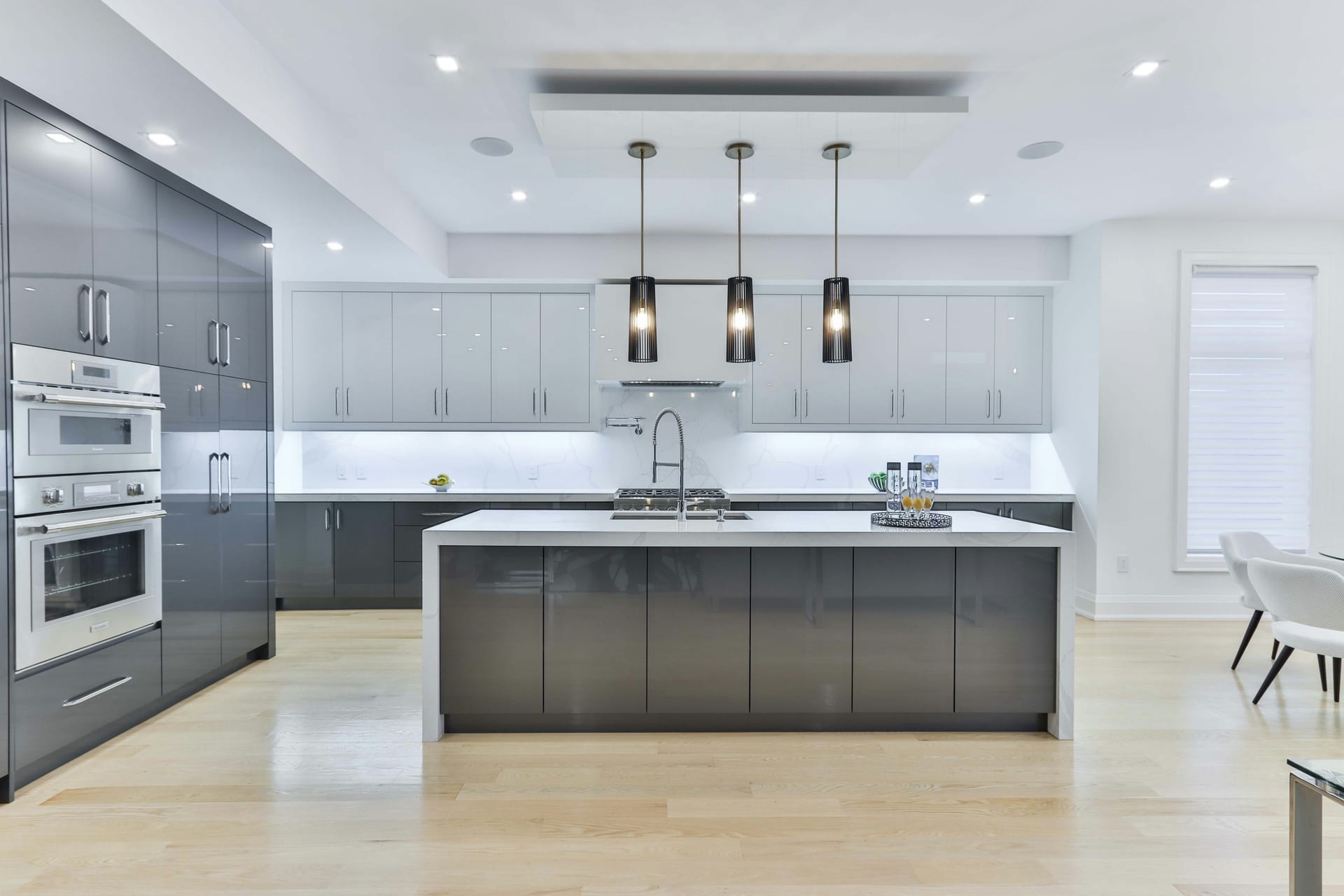 Modern Houston kitchen featuring two-tone cabinetry, brass hardware, waterfall quartzite island, and warm natural materials.