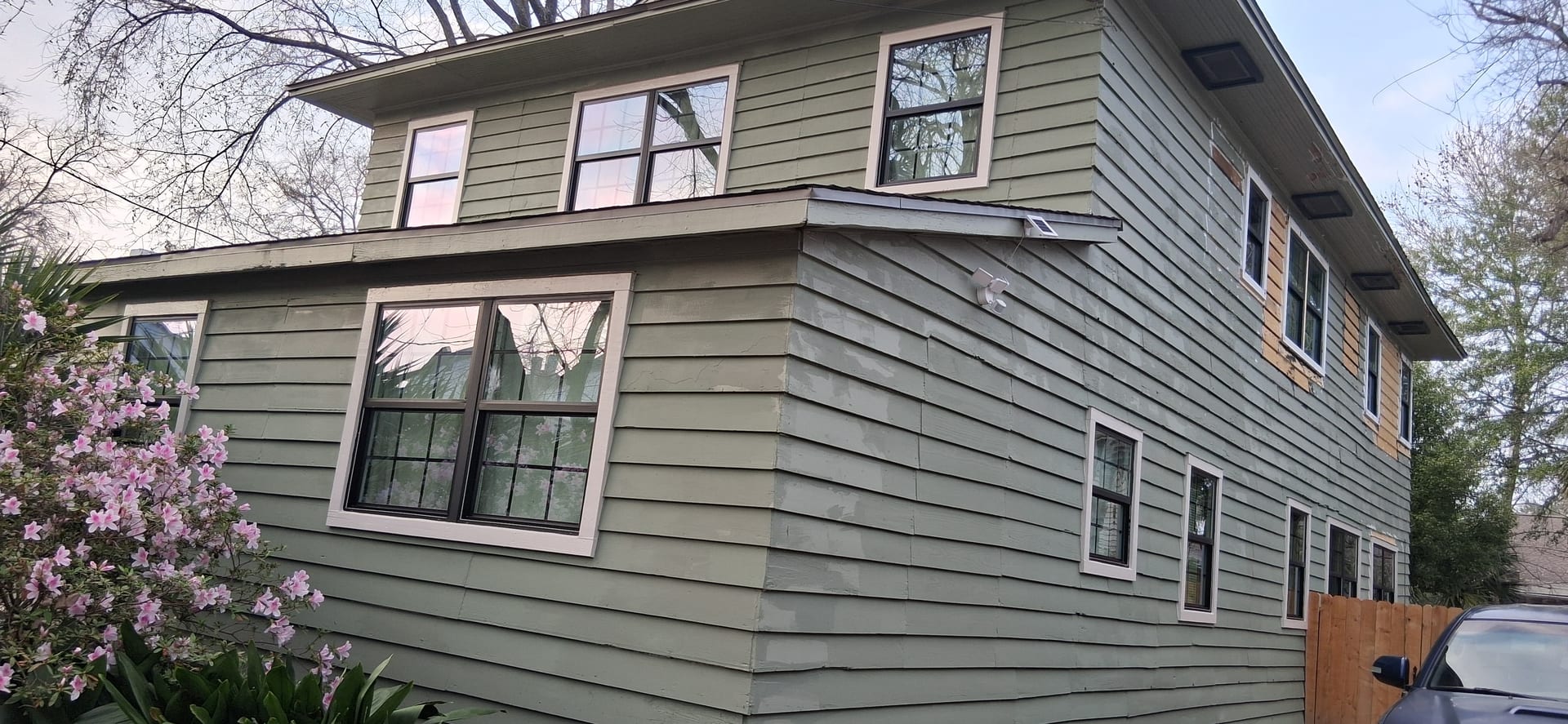 Front exterior of a two-story house after window installation and siding repair work.